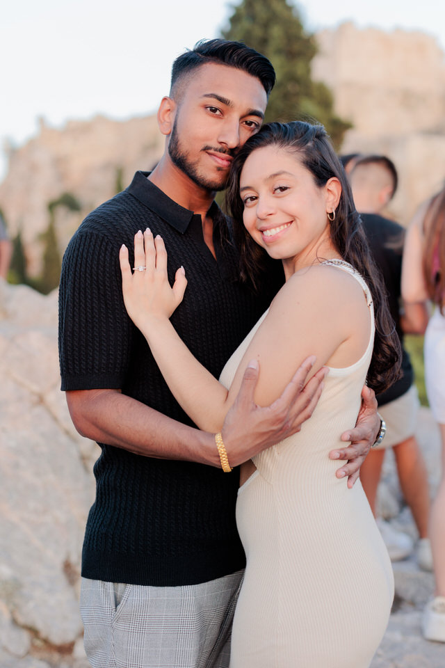 My beautiful young couple came to Greece from the United States for summer vacation. Alexia & Carson have been together since high school, and now the decisive moment has come. The marriage proposal. The big bang in the life of a couple in love. Engagement in Athenian Riviera Proposal Photo Session Greece Carson chose a fantastic spot on the Athenian Riviera for the proposal photo session. The engagement in Athenian Riviera happens at a specific time so that we would have perfect flattering natural light. Smiles and love overflowed in this marriage proposal, and engagement captured everything organically and bright. I will be thrilled if you also want me to be a tiny part of an emotionally powerful scene as your marriage proposal. You can find the procedure we will follow here on the engagement day. Wedding Proposal Filopappou Hill Marriage Photoshoot Athens 0042