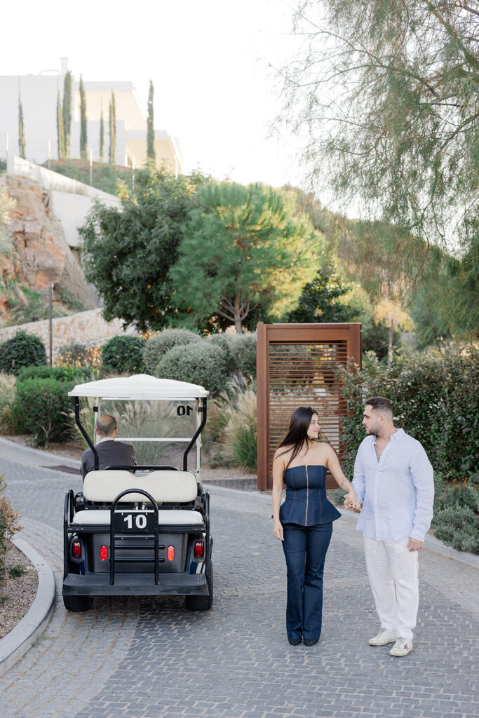A stylish couple walking hand-in-hand at a premium resort, captured by luxury surprise proposal photographer Ignatios Kourouvasilis. Luxury Surprise Proposal Photographer Ignatios Kourouvasilis