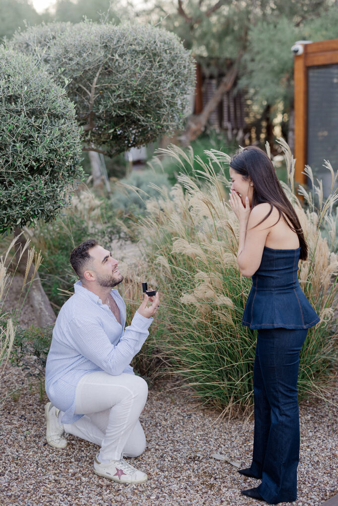 The exact moment of a secret engagement, with a man on one knee proposing to his joyful partner, captured by luxury surprise proposal photographer Ignatios Kourouvasilis. Luxury Surprise Proposal Photographer Ignatios Kourouvasilis